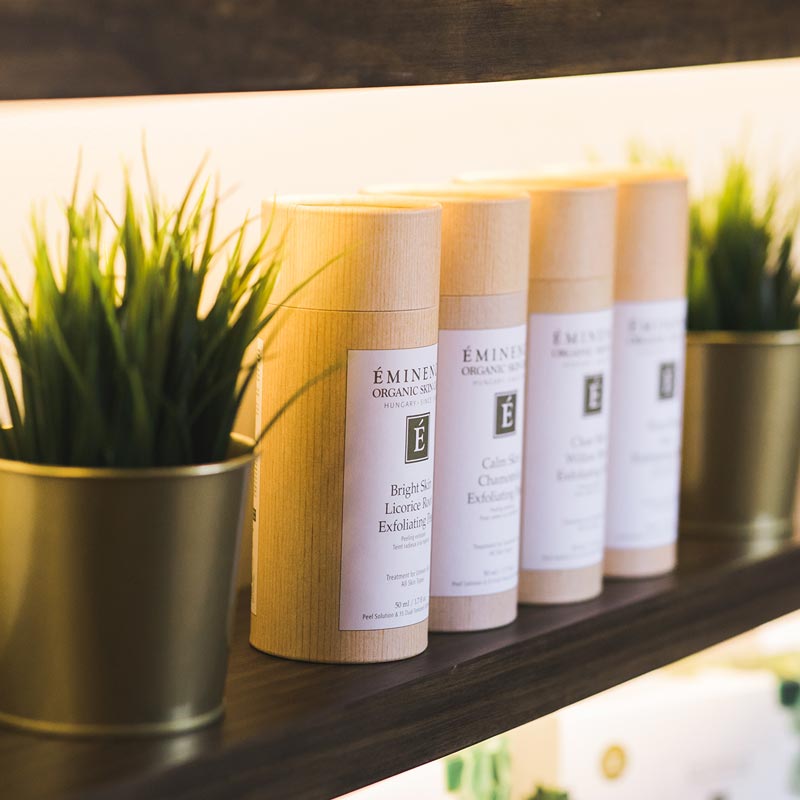 Display of Eminence Organic Skin Care products in cylindrical packaging on a shelf.